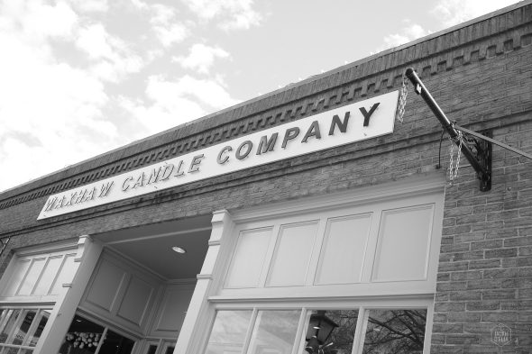 Black and white photo of a building with a sign reading "Yankee Candle Company." The entrance features large windows and an open door.