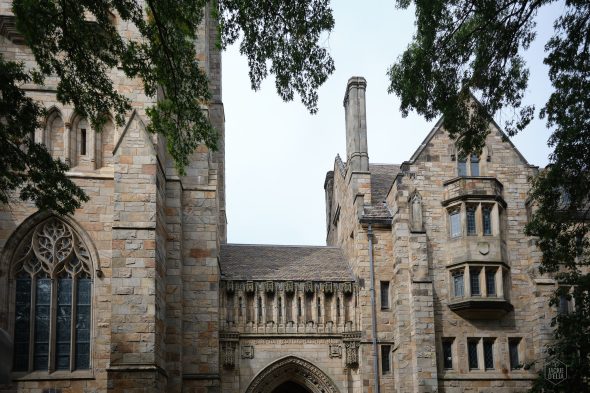 Stone building with Gothic architectural elements, including arched windows and intricate stonework, surrounded by trees.
